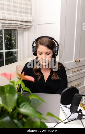 Eine Frau konzentrierte sich intensiv auf Podcast-Aufnahmen in ihrem Heimstudio Stockfoto