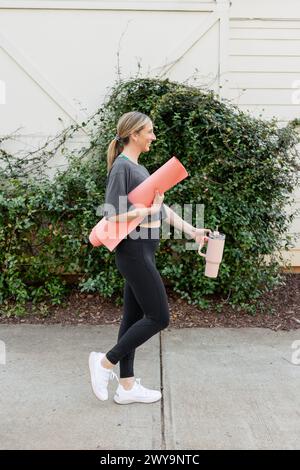 Lächelnde Frau mit Yogamatte draußen Stockfoto