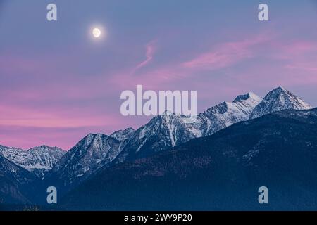 Rosafarbener Sonnenuntergang und Mondaufgang über den Mission Mountains Stockfoto