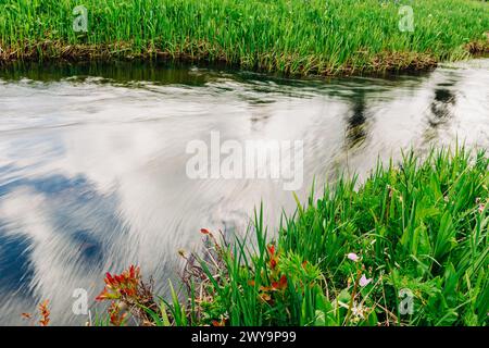 Langzeitaufnahme des Bachwassers mit Reflexionen des Himmels und der Wolken Stockfoto