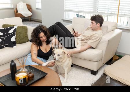 Junge Paare, zu Hause, mit ihrem Hund und am Telefon Stockfoto