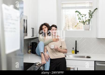 Herzliche Umarmung eines fröhlichen Paares während einer gemütlichen Kaffeepause in der Küche Stockfoto