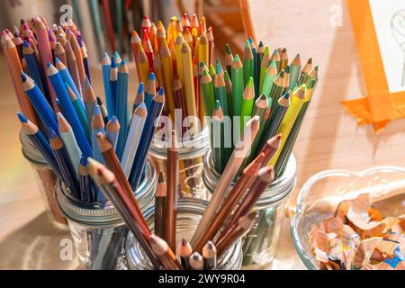 Gläser mit farbigen Bleistiften in der Sonne - Art Studio Schreibtisch farbenfroh warm hell Stockfoto