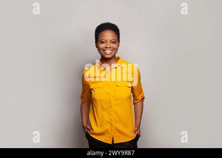 Selbstbewusste erfolgreiche Frau lächelt und hat Spaß vor dem Hintergrund des Wandbanners im Studio Stockfoto