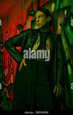 Eine Frau steht vor einer lebhaften Wand, die mit Graffiti bedeckt ist Stockfoto