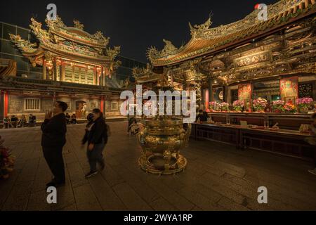 Ein aufwendig dekorierter Longshan-Tempel bei Nacht, gefüllt mit Blumen und goldenen Statuen Stockfoto