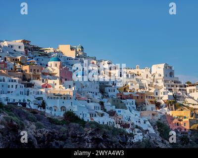 Blick in Richtung der blauen Kuppelkirchen der Auferstehung des Herrn und des Heiligen Spyridon bei Sonnenuntergang, Oia Village, Santorini Thira Island, Kykladen, griechischer IS Stockfoto