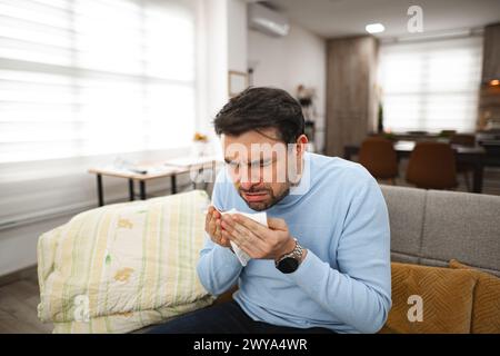 Der kranke Mann niest den ganzen Tag zu Hause Stockfoto