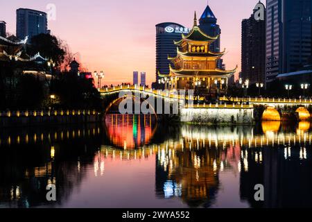 Guiyang, China - 09. Februar 2022: Der berühmte Jiaxiu-Turm und die Fuyu-Brücke spiegeln sich auf dem Fluss im Herzen des Stadtzentrums von Guiyang im Südwesten von C Stockfoto