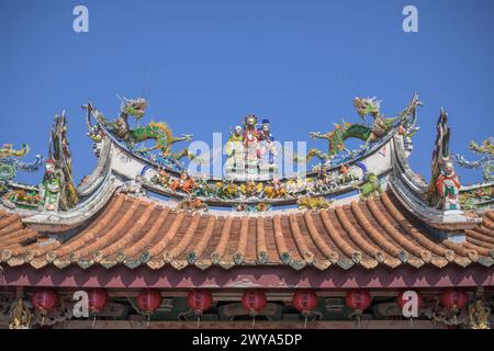 Eine lebendige Darstellung traditioneller chinesischer Tempeldächer mit mythischen Kreaturen vor einem klaren blauen Himmel im Mazu-Tempel Stockfoto