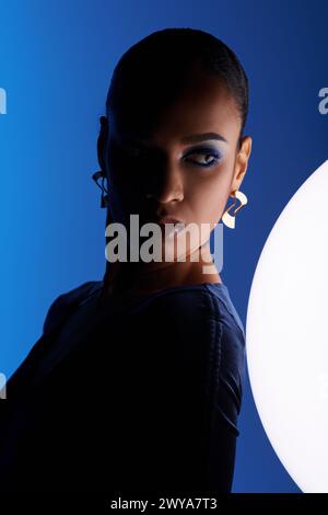 Eine junge afroamerikanische Frau, die von einer weißen Kugel in einem Studio-Setting gefesselt ist. Stockfoto