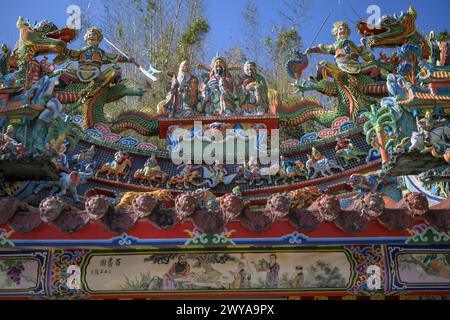 Eine lebendige Drachenskulptur auf einem Tempeldach mit blauem Himmel und Pinienholz Stockfoto