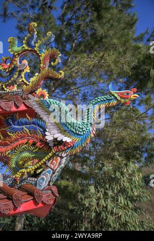 Eine lebendige Drachenskulptur auf einem Tempeldach mit blauem Himmel und Pinienholz Stockfoto