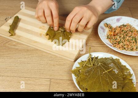 Frau Hände, die Wrap mit Reiszutat zubereiten. Griechische oder türkische Speisen Yaprak Sarma oder Dolma Zubereitung. Traditionelle ägäische Küche in der Türkei. Stockfoto