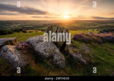 Eine Felsformation, bekannt als Knuckle Stone bei Carhead Rocks, unterhalb der Stanage Edge, an einem Sommerabend, wenn die Sonne über dem Horizont untergeht. Stockfoto