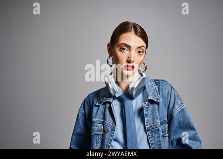 Eine junge Kaukasierin mit brünetten Haaren in Jeansjacke und Ohrringen, die Stil und Selbstvertrauen ausstrahlt. In Kopfhörern Stockfoto