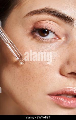 Eine Nahaufnahme einer jungen Kaukasierin mit sauberer Haut, die Serum mit kosmetischer Pipette aufträgt Stockfoto