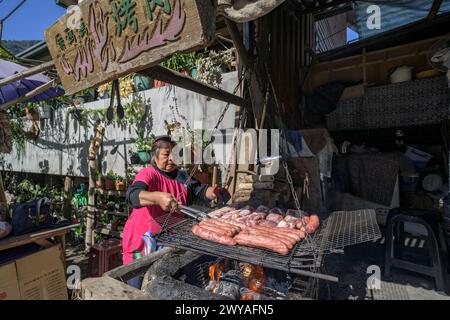 Straßenverkäufer im Freien, der Würstchen auf einem Grill grillt Stockfoto