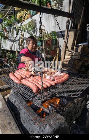 Straßenverkäufer im Freien, der Würstchen auf einem Grill grillt Stockfoto