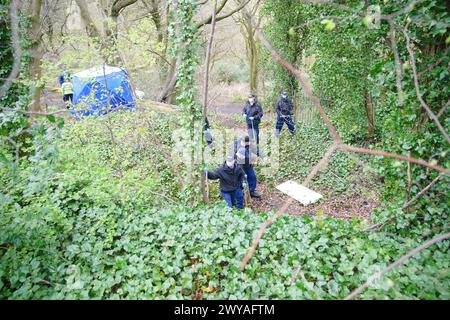 Polizeibeamte durchsuchen ein forensisches Zelt in Kersal Dale in der Nähe von Salford, Greater Manchester, wo eine große Untersuchung eingeleitet wurde, nachdem am Donnerstagabend menschliche Überreste gefunden wurden. Die Polizei von Greater Manchester (GMP) sagte, dass Beamte von einem Mitglied der Öffentlichkeit gerufen wurden, der einen „unbekannten Gegenstand in Plastik gewickelt“ fand. Bilddatum: Freitag, 5. April 2024. Stockfoto