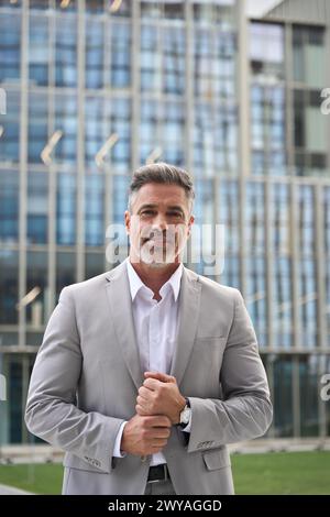 Selbstbewusster, reifer Geschäftsmann, der einen Anzug trägt und im Freien steht. Vertikales Hochformat. Stockfoto