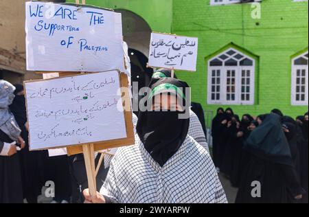 Srinagar, Indien. April 2024. Ein muslimisches Mädchen aus Kaschmir hält Plakate, die die Unterstützung Palästinas während einer Kundgebung zum Quds-Tag zeigen. (Al-Qud) ist der arabische Name für Jerusalem. Der Al Quds Day, eine Initiative des verstorbenen iranischen Revolutionsführers Ayatollah Ruhollah Khomeini, wird weltweit am letzten Freitag des Heiligen Monats Ramadan gefeiert, um die Unterstützung der Palästinenser zu zeigen und Israel zu verurteilen. Quelle: SOPA Images Limited/Alamy Live News Stockfoto