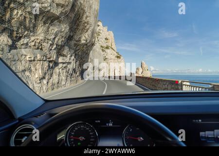 Aus dem Inneren des Autos die atemberaubende, hochgelegene Straße an den Klippen entlang der Küste von Ligurien, Italien Stockfoto