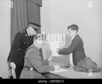 DER 14-JÄHRIGE JUNGE IST MITGLIED DER ROYAL MARINES BAND. 8. JANUAR 1942, SCARBOROUGH. DER 14-JÄHRIGE REGINALD DAVID WARDEN TRAT DER ROYAL MARINE SCHOOL OF MUSIC IN SCARBOROUGH BEI UND WURDE IHR JÜNGSTES MITGLIED. DIE SCHULE VERSORGT ALLE MUSIKER UND MARINEBANDS MIT HM-SCHIFFEN UND LANDBASEN. - Der 14-jährige Reginald David Warden übergibt den Brief an den zuständigen Offizier der Royal Marine School of Music und gibt seinem Vater die Zustimmung, als Musiker bei den Marines zu sein. , Stockfoto