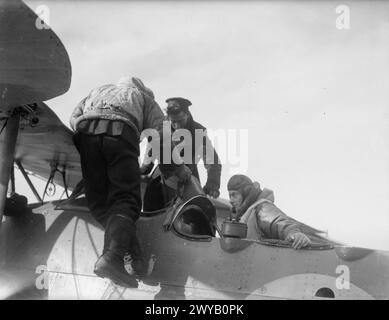 LUFTWAFFENAKTIVITÄTEN DER FLOTTE BEI HMS SPARROWHAWK, ROYAL MARINEFLUGSTATION HATSTON. MÄRZ 1942. - Die Marinestattung steigt aus dem Cockpit, während der Pilot des Fairey-Schwertfisches einsteigt. Der Beobachter sitzt auf seinem Platz mit Aldis Signalleuchte bereit. , Stockfoto