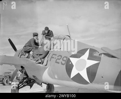 US-MARINEFLIEGER KOMMEN IN GROSSBRITANNIEN AN. APRIL 1942: ROYAL MARINEFLUGSTATION HATSTON. VIER GESCHWADER VON US NAVY, BESTEHEND AUS 9 DOUGLAS TBD DEVASTATOR TORPEDOBOMBERN, 9 GRUMMAN F4F WILDCAT JAGDFLUGZEUGEN UND 29 VOUGHT SB2U VINDICATOR SCOUT BOMBERN, KAMEN IN HATSTON AN, UM MIT DER FLOTTENLUFTWAFFE ZUSAMMENZUARBEITEN. MIT IHNEN SIND 65 US-MARINE-PILOTEN UND 200 ODD-RADIOMEN, LUFTWAFFENSCHÜTZER UND RESERVEN. - Ein US-Seemann erklärt den Grumman-Kämpfer ein paar britischen Seeleuten. , Stockfoto