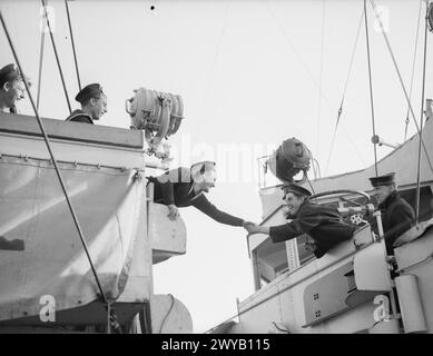 ANKUNFT DER ERSTEN FLOTTE AMERIKANISCHER ZERSTÖRER FÜR DIE ROYAL NAVY. 28. SEPTEMBER 1940, ROYAL DOCKYARD, DEVONPORT. DIE FLOTTE, DIE VON DER US-REGIERUNG IM RAHMEN DES ABKOMMENS ÜBERGEBEN WURDE, WAR VOLLSTÄNDIG VON BRITISCHEN BESATZUNGEN BESETZT. - Händeschütteln von einer Ankunft zur anderen. , Stockfoto