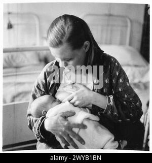 TAUFE VON BABYS IM LAGER BELSEN – Originalunterschrift aus der Kriegszeit: Raissa Dorochova [Russland] ernährt ihr Kind. Fotografisches negativ, britische Armee, 21. Armeegruppe Stockfoto