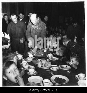 TRUPPEN-WOHLWOLLEN-PARTY FÜR NIEDERLÄNDISCHE KINDER - Originaltitel aus der Kriegszeit: Brig B. Kennett, MBE CSO, CORPS schneidet den Kuchen, mit SJT Travis, der die Kuchen gemacht hat, rechts. Fotografisches negativ, britische Armee, 21. Armeegruppe Stockfoto