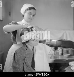 AUSBILDUNG VON QUEEN'S NURSES: AUSBILDUNG VON DISTRICT NURSES AM QUEEN'S INSTITUTE OF DISTRICT NURSES, GUILDFORD, SURREY, ENGLAND, GROSSBRITANNIEN. 1944: am Queen's Institute of District Nursing in Guildford wird ein Trainee District Nurse den Kopf einer Patientin binden. , Stockfoto