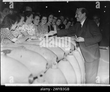 CLEMENT ATTLEE BESUCHT KÖNIGLICHE KAMPFMITTELFABRIK HEREFORD, HEREFORDSHIRE, ENGLAND, Großbritannien, JULI 1941 - Lord Privy Seal, Mr. Clement Attlee, lächelt, während er bei einem Besuch der ROF Hereford am Freitag, den 11. Juli 1941, die Hände schüttelt. Er lehnt sich über einen Haufen Muscheln, um die Arbeiter zu begrüßen. , Attlee, Clement Richard Stockfoto