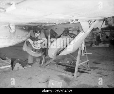 MÄNNER FÜR DIE FLOTTENLUFTWAFFE FÜR DIE ZUKUNFT. 15. UND 16. DEZEMBER 1943, ROYAL AIR TRAINING ESTABLISHMENT, NEWCASTLE-UNDER-LYME. JUNGE BRITEN, DIE SICH AUF EINEN WICHTIGEN JOB VORBEREITEN, JUNGEN AB 15 JAHREN, DIE FÜR DIE FLOTTENFLUGWAFFE TRAINIEREN. - Luftfahrtausbilder, die auf dem einziehbaren Unterwagen eines Jagdflugzeugs arbeiten. , Stockfoto