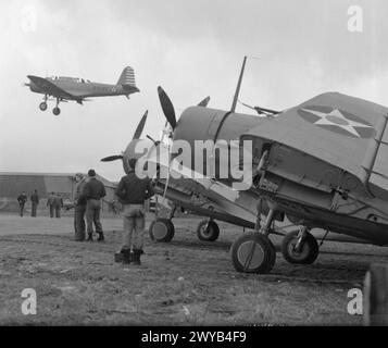 US-MARINEFLIEGER KOMMEN IN GROSSBRITANNIEN AN. APRIL 1942: ROYAL MARINEFLUGSTATION HATSTON. VIER GESCHWADER VON US NAVY, BESTEHEND AUS 9 DOUGLAS TBD DEVASTATOR TORPEDOBOMBERN, 9 GRUMMAN F4F WILDCAT JAGDFLUGZEUGEN UND 29 VOUGHT SB2U VINDICATOR SCOUT BOMBERN, KAMEN IN HATSTON AN, UM MIT DER FLOTTENLUFTWAFFE ZUSAMMENZUARBEITEN. MIT IHNEN SIND 65 US-MARINE-PILOTEN UND 200 ODD-RADIOMEN, LUFTWAFFENSCHÜTZER UND RESERVEN. - Im Vordergrund mit gefalteten Flügeln sind US-Devastator-Torpedobomber, gerade landet ein Vought-SB2U-Vindicator-Scout-Bomber. US-Bodenpersonal ist anwesend. , Stockfoto