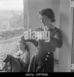 JUNGE WANDERER IN YORKSHIRE: DIE ARBEIT DER YOUTH HOSTEL ASSOCIATION IN WARTIME, MALHAM, YORKSHIRE, ENGLAND, VEREINIGTES KÖNIGREICH, 1944 – im Jugendherberge in Malham ölt Nell Petrie (von Jarrow) ihre Wanderschuhe, bevor sie sich auf eine Tageswanderung macht. Neben ihr überprüft ein Jugendfreund den Inhalt ihres Rucksacks. , Stockfoto