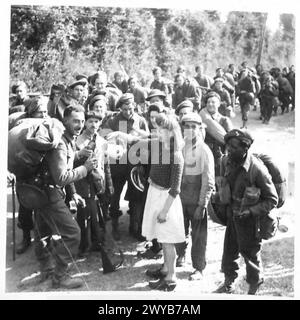 BILDER DER NORMANDIE, VERSCHIEDENE - Originalunterschrift aus der Kriegszeit: Eine Szene auf einer Straße in der Normandie, während Truppen der Reserve-Holding-Einheit auf einer Straße halten, um einen Begrüßungsdrink Cidre zu trinken, der ihnen von französischen Bauern angeboten wird. Fotografisches negativ, britische Armee, 21. Armeegruppe Stockfoto