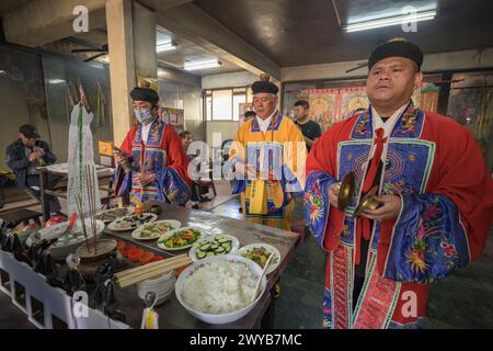 Ein traditioneller Schamane, der ein Ritual mit Opfergaben an die Vorfahren auf einem Altar im Donggyue Hall Tempel durchführt Stockfoto