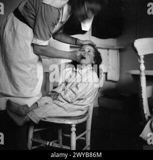 KINDERGARTEN: LEBEN IM ALTEN HERRENHAUS, WENDOVER, BUCKINGHAMSHIRE, ENGLAND, 1944 - Ein kleines Kind wird von einer der Schwestern des alten Herrenhauses, Wendover, die Zähne gereinigt. , Stockfoto