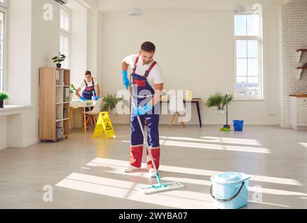 Arbeiter aus dem Reinigungsdienst, die Boden wischen und Möbel in modernen Häusern stauben Stockfoto