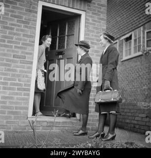 AUSBILDUNG VON QUEEN'S NURSES: AUSBILDUNG VON DISTRICT NURSES AM QUEEN'S INSTITUTE OF DISTRICT NURSES, GUILDFORD, SURREY, ENGLAND, GROSSBRITANNIEN. 1944 – Eine Trainee District Nurse (rechts) begleitet eine qualifizierte District Nurse bei einem Hausbesuch. Sie werden an der Tür von einer Hausfrau begrüßt. Es ist wahrscheinlich, dass dies die Mutter des jungen Mädchens ist, das sich von einer Lungenentzündung erholt, wie in D 23115 zu sehen ist. , Stockfoto