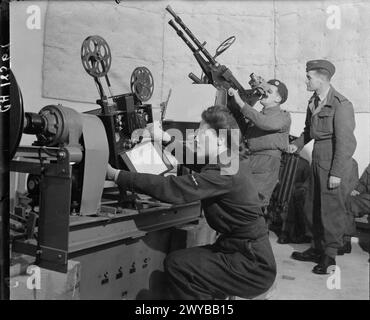 Ein Mitglied des Royal Air Force Regiments erhält eine Ausbildung in einem Kuppelabwehrlehrer bei der RAF Leuchars, während ein Mitglied der Women's Auxiliary Air Force Zielfilme projiziert. Stockfoto