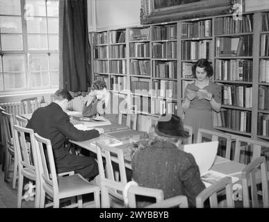 NIGHT SCHOOL GIRL: ABENDKURSE IN WARTIME LONDON, C 1940 - Mrs Ridley studiert ein Buch in der Bibliothek des City Literary Institute, London. Mrs. Ridley nahm an Abendstunden in Gesang und Drama Teil. , Stockfoto