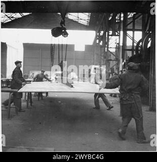 Foto von Männern in Tyneside Shipyards, 1943, die eine große Metallplatte heben und sie zum Schneiden in eine Schermaschine bringen. Stockfoto