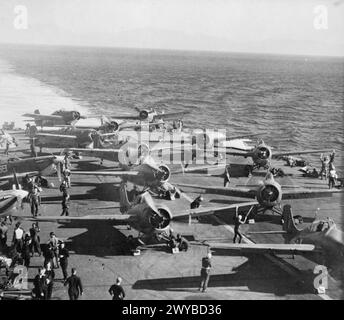 HMS „BEI DER ARBEIT“. OKTOBER 1943, AN BORD VON FORMIDABLE, AUF SEE MIT ANDEREN SCHIFFEN DER ROYAL NAVY. IHRE FLUGZEUGE SIND DIE "AUGEN" DER FLOTTE, DIE NACH U-BOOTEN AUSSCHAU HALTEN UND BEREIT SIND, VERSUCHTE LUFTANGRIFFE ABZUWEHREN. - Eine Reihe von Jägern, die sich auf dem Flugdeck der HMS FORMIDABLE aufwärmen, mit Bodenbesatzungen, die für die Freilassung bereit sind. , Stockfoto