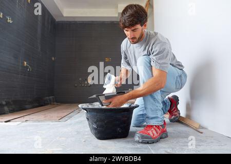 Maurer, der Fliesenkleber zum Fliesen aufträgt. Bau eines Wohngebäudes. Donostia. San Sebastian. Gipuzkoa. Baskenland. Spanien. Stockfoto