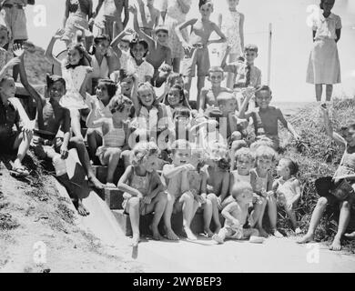 IM STANLEY INTERNIERUNGSLAGER, HONGKONG. AUGUST UND SEPTEMBER 1945. Kleine Kinder, die im Stanley Internierungslager interniert sind, begrüßen die ersten Kontingente der Royal Navy. Obwohl sie unterernährt waren und Anzeichen für die Daseinsberechtigung unter den Japanern zeigten, waren diese Kinder bemerkenswert fit. Jeder im Lager hatte dazu beigetragen, die Kinder gesund zu halten. Baby Gerald Ward, 13 Monate alt und im Lager geboren, ist an der Front der Gruppe. , Stockfoto