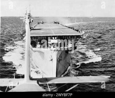 HMS BITER ESKORTIERT Einen KONVOI, MÄRZ 1944 - Luftansicht des Escortträgers HMS BITER aus einem ihrer Fairey-Schwertfischflugzeuge direkt nach dem Start. Auf dem Deck stehen zwei Wildcat-Jäger und in der Ferne Schiffe des Konvois bereit. Royal Navy, BITER (HMS), Royal Navy, Fleet Air Arm Stockfoto